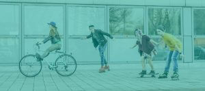 Vier Jugendliche; auf dem Rad, dem Skateboard und Rollschuhen